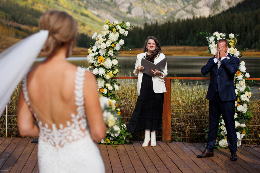 The groom reacts as the bride walks down the aisle